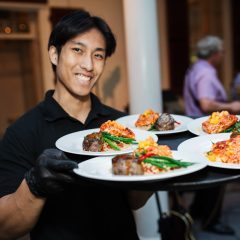 Seedling and Sage wedding server carrying a tray of entrees