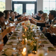 Candlelit dinner table at a wedding reception with guests toasting their glasses