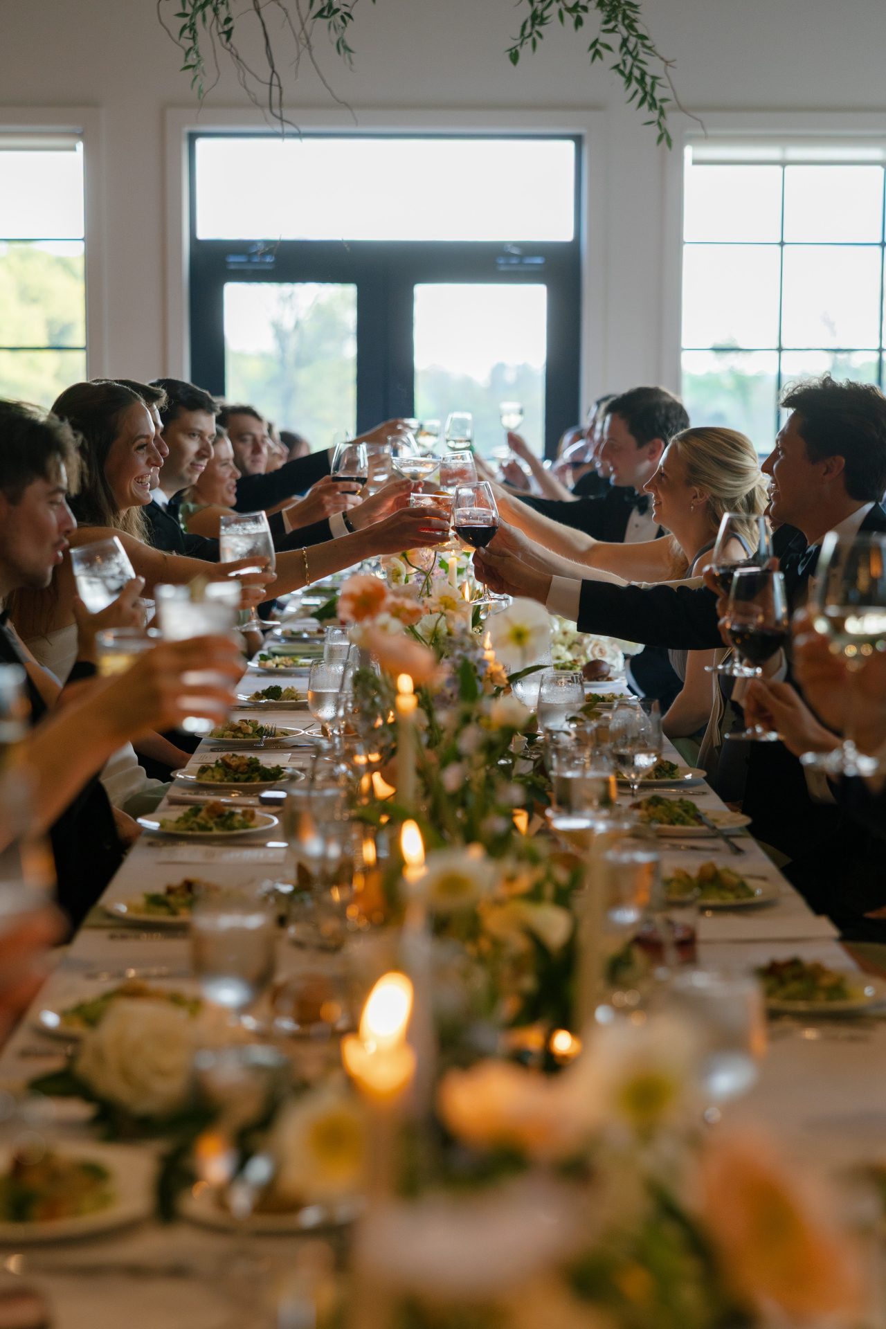 Candlelit dinner table at a wedding reception with guests toasting their glasses