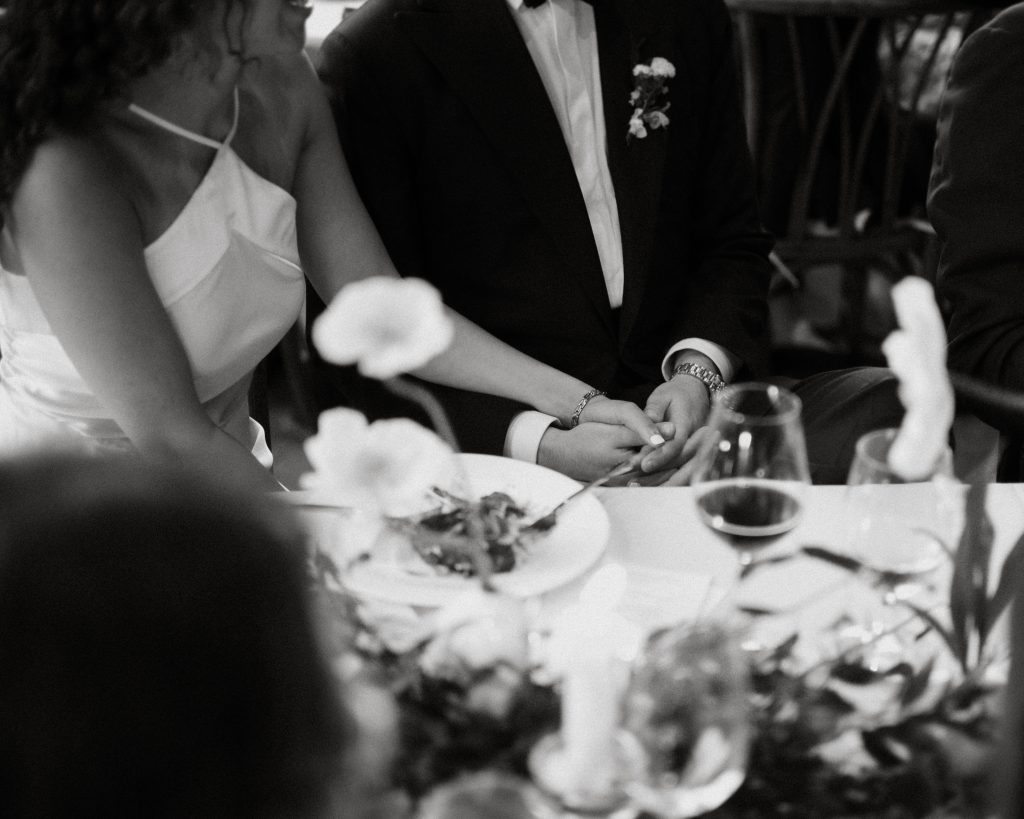 Couple sitting hand in hand at wedding reception dinner in Philadelphia